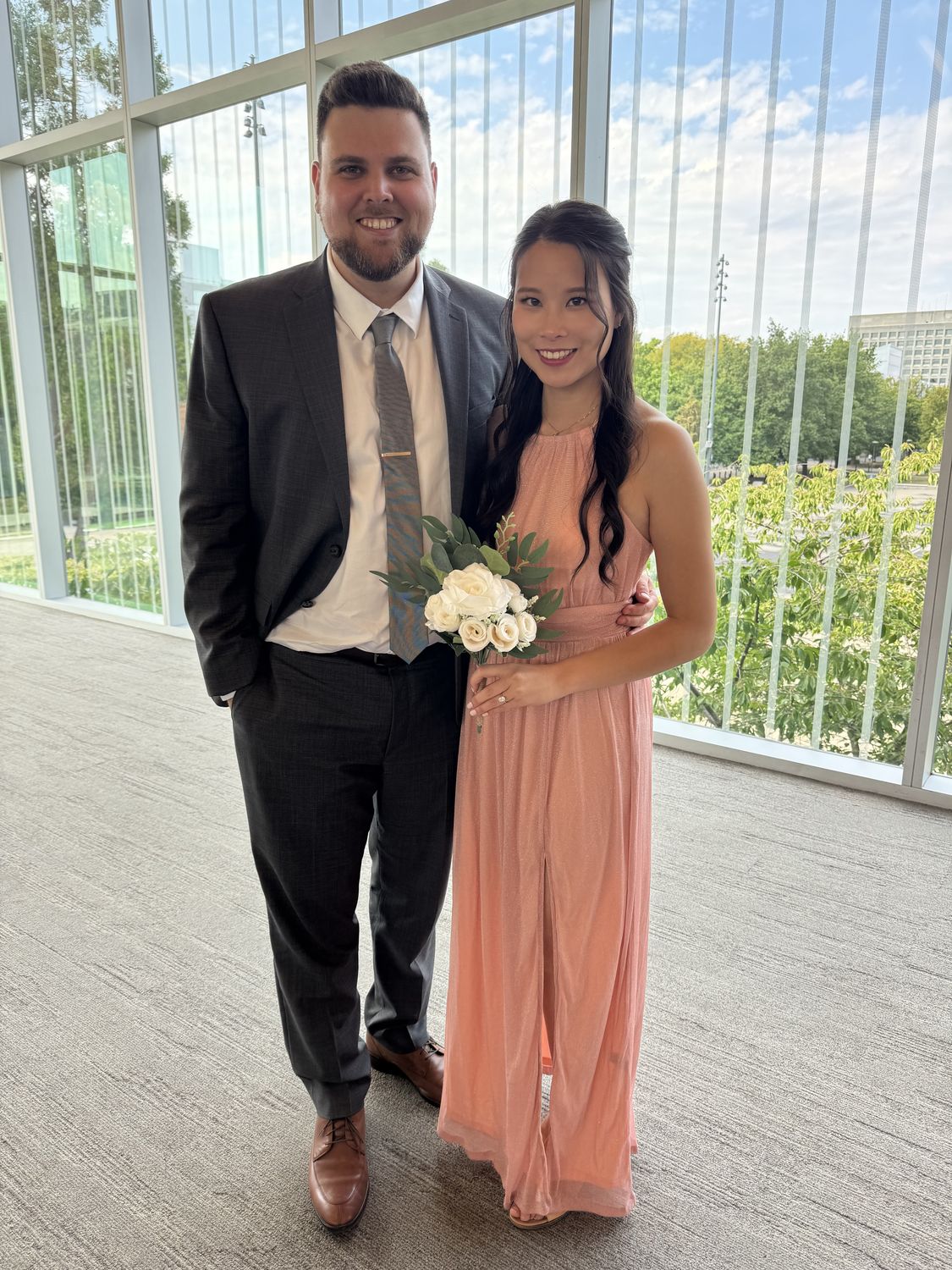 Natalie and Eric dressed up together, Natalie holding a bouquet of white roses