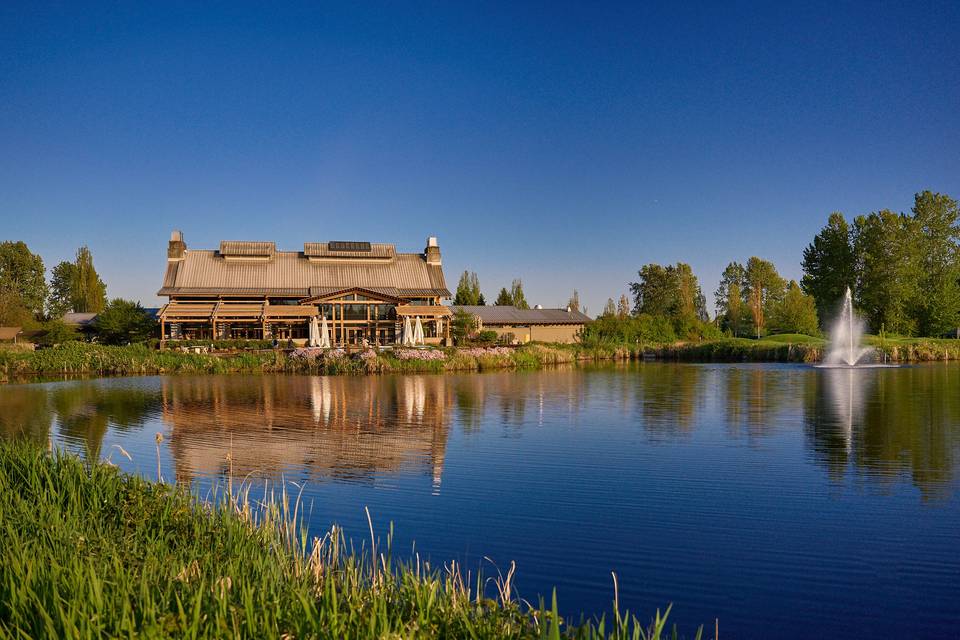 Riverway Clubhouse seen across the pond at golden hour, with a fountain to the right